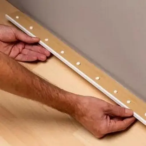 Contractor mounting wood board on wall using no more nails adhesive to demonstrate weight holding capacity for heavy fixtures